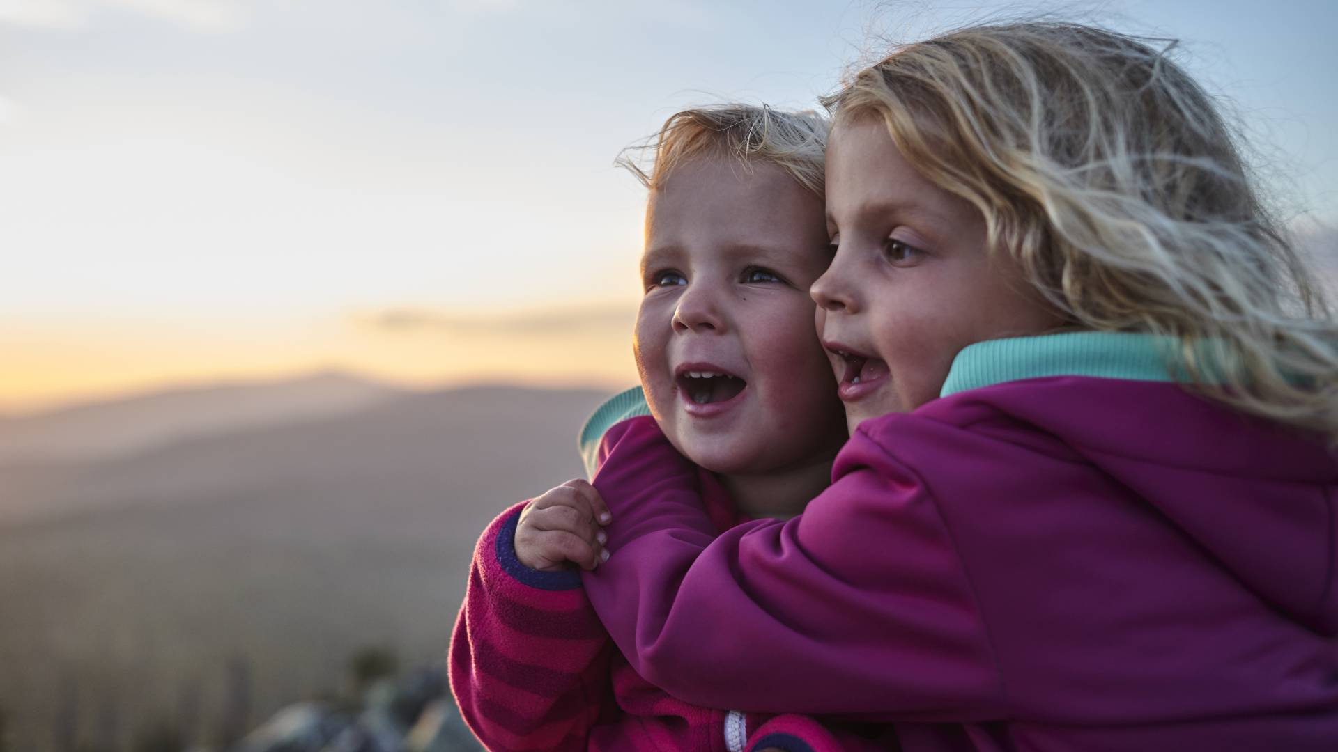 Kinder blicken vom Berg in die Landschaft