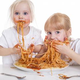 Mädchen essen Spagetti mit den Händen