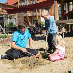 Vater spielt mit seinen Kindern im Sandkasten