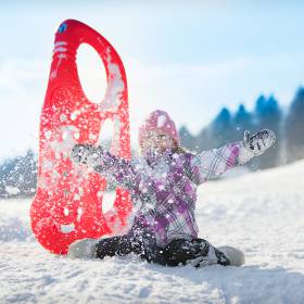 Kind spielt mit Rodel im Schnee