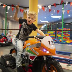 Junde und Mädchen fahren auf der Indoor Kart Bahn