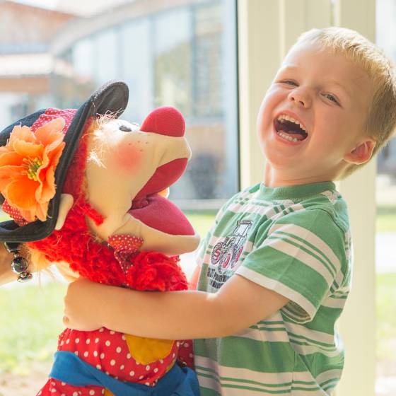 Kind spielt mit Maskottchen Happy
