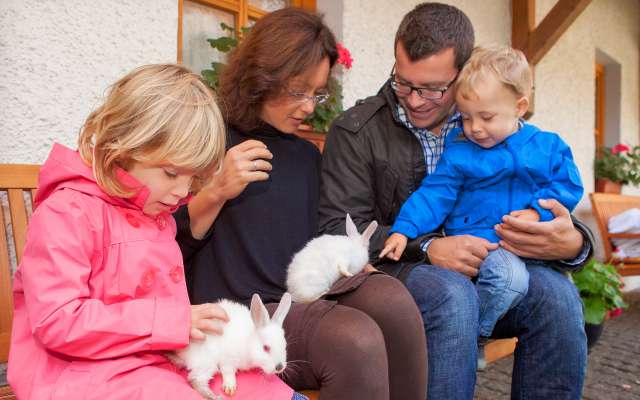 Familie streicheln Hasen im Streichelzoo des Familienhotels Schreinerhof