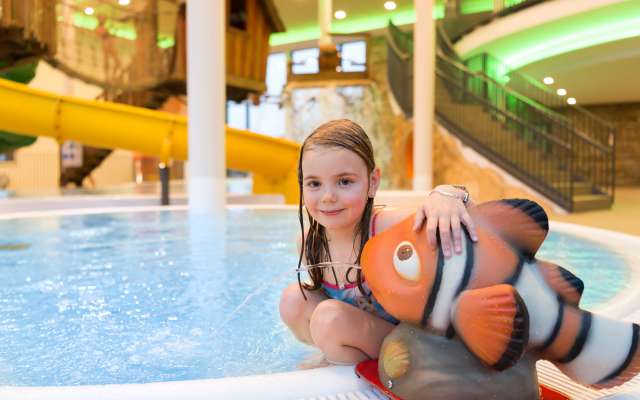 Kind sitzt an Wasserspiel in der Wellnesswelt des Familienhotels Schreinerhof