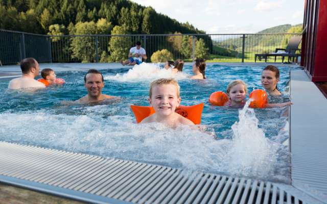 Familie schwimmt im Außenpool im Familienhotel Schreinerhof