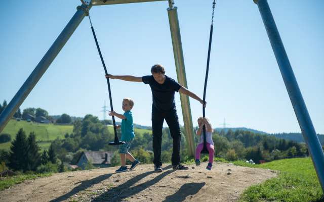 Vater hilft seinen Kindern beim Schaukeln