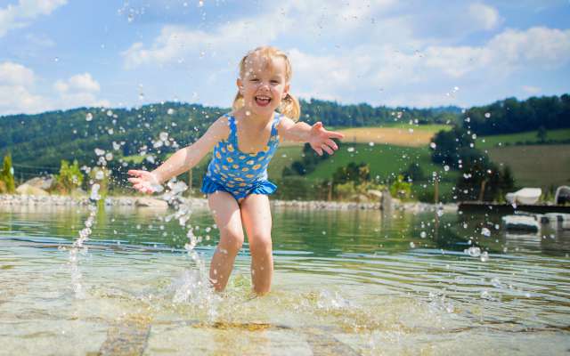 Mädchen spielt im Naturbadeteich des Familienhotels Schreinerhof