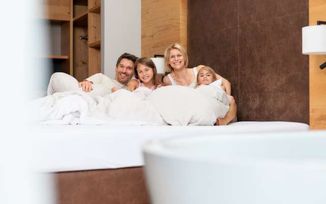 Familie kuschelt im Bett im Familienhotel Schreinerhof