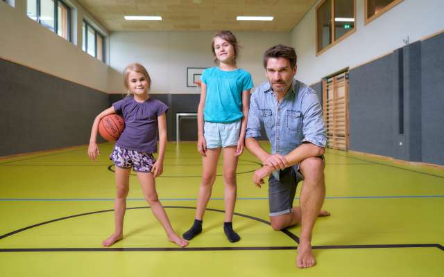 Vater mit Töchtern mit Basketball in der Turnhalle im Familienhotel Schreinerhof
