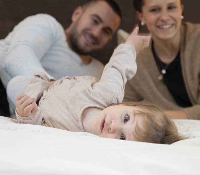 Kleines Mädchen liegt im Bett im Familienhotel Schreinerhof