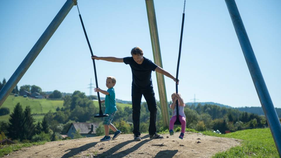 Vater hilft Kindern auf die Schaukel