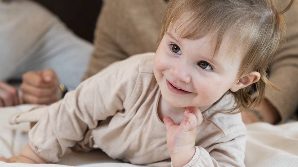 Baby blickt lächelnd in die Kamera im Familienhotel Schreinerhof